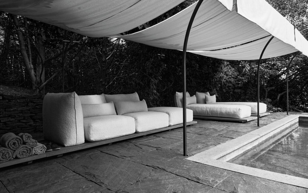 Black and White photo featuring sofas under a canopy outside.